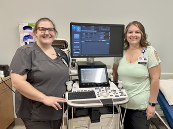 Picture of a female Ultrasound Tech showing a pregnant female an ultrasound of her baby.